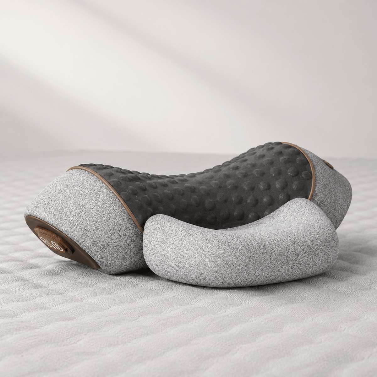 Light gray Thera Pillow heated neck traction massager on a bed